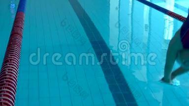 女孩游泳者在游泳池里潜水。 女游泳运动员潜入游泳池游泳。 上景。
